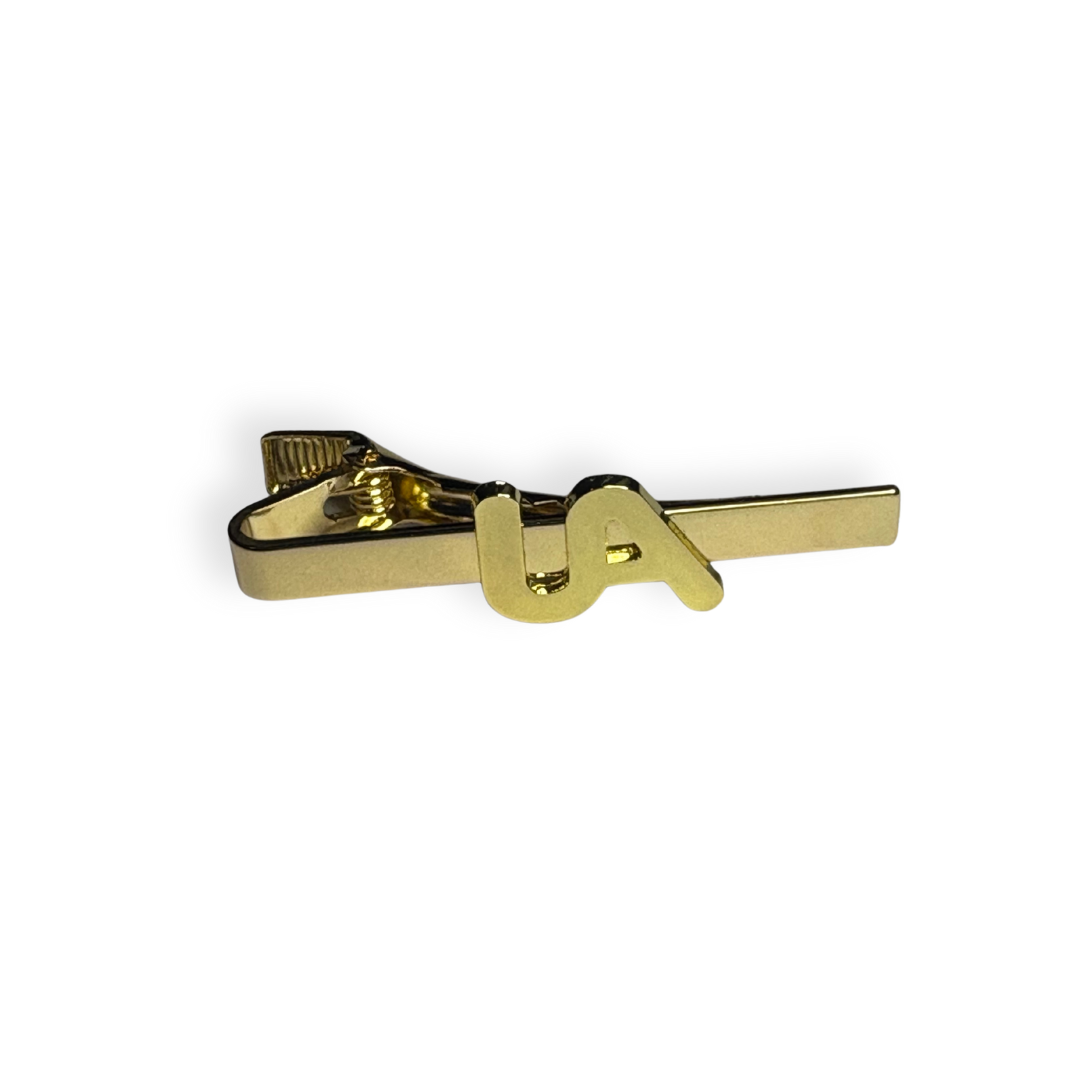 Gold  metal tie bar with raised UA logo, shown on a white background.